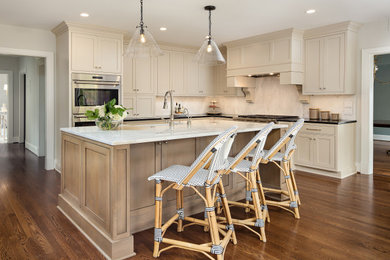 Large transitional l-shaped medium tone wood floor and brown floor eat-in kitchen photo in Other with shaker cabinets, granite countertops, stainless steel appliances, an island, a farmhouse sink, beige cabinets, beige backsplash, stone slab backsplash and black countertops