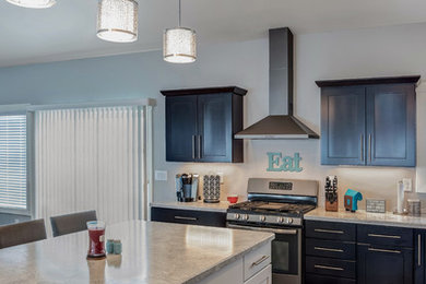 Open concept kitchen - large transitional l-shaped medium tone wood floor open concept kitchen idea in Other with a double-bowl sink, shaker cabinets, dark wood cabinets, quartzite countertops, stainless steel appliances and an island