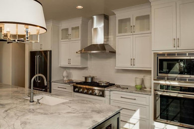 Inspiration for a large contemporary single-wall dark wood floor and brown floor open concept kitchen remodel in Portland Maine with an undermount sink, shaker cabinets, white cabinets, quartz countertops, white backsplash, subway tile backsplash, stainless steel appliances and an island