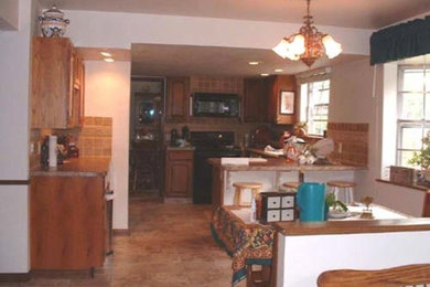 Kitchen - traditional terra-cotta tile kitchen idea in Denver with raised-panel cabinets, medium tone wood cabinets, black appliances and an island