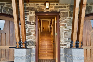 Ejemplo de entrada rústica con puerta simple y puerta de madera clara