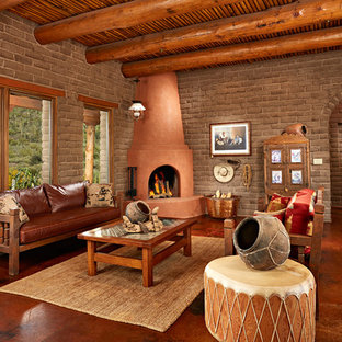 Repräsentatives, Abgetrenntes, Großes, Fernseherloses Mediterranes Wohnzimmer mit Eckkamin, verputztem Kaminsims, brauner Wandfarbe und Betonboden in Phoenix