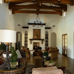 Inspiration for a large mediterranean formal enclosed living room in Phoenix with white walls, medium hardwood flooring, a standard fireplace, a concrete fireplace surround and brown floors.