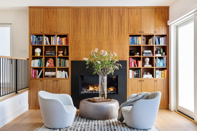 Trendy light wood floor and wood wall living room photo in San Francisco with a metal fireplace