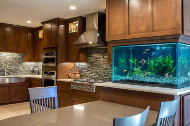 Eat-in kitchen - mid-sized traditional l-shaped porcelain tile eat-in kitchen idea in Dallas with a farmhouse sink, shaker cabinets, medium tone wood cabinets, quartz countertops, brown backsplash, glass tile backsplash, stainless steel appliances and no island