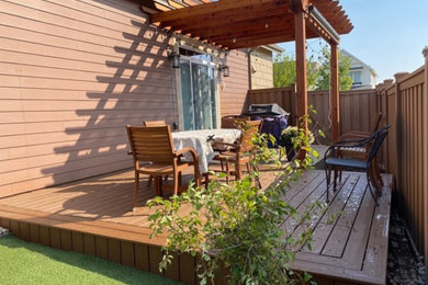 Example of a mid-sized classic side yard ground level privacy and wood railing deck design in Denver with a pergola