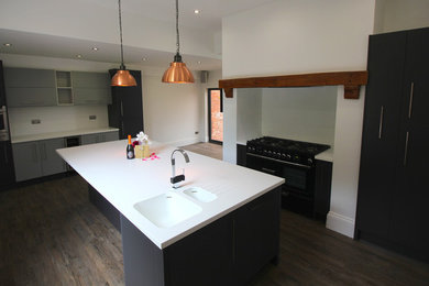 Design ideas for a large contemporary l-shaped open plan kitchen in West Midlands with an integrated sink, grey cabinets, composite countertops, laminate floors, an island and brown floors.