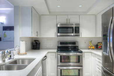 Mid-sized minimalist u-shaped light wood floor eat-in kitchen photo with an undermount sink, shaker cabinets, white cabinets, quartz countertops, white backsplash, subway tile backsplash and stainless steel appliances