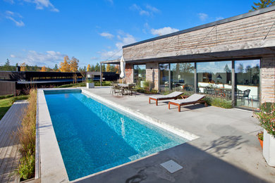 This is an example of a large scandinavian front yard rectangular pool in Stockholm with concrete slab.