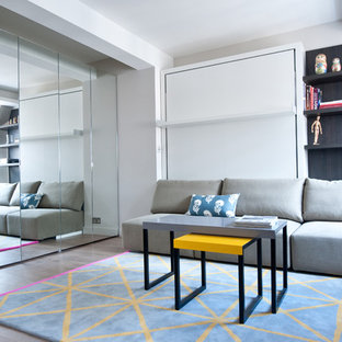 Ispirazione per un piccolo soggiorno design aperto con pareti grigie, parquet chiaro, nessun camino e TV a parete