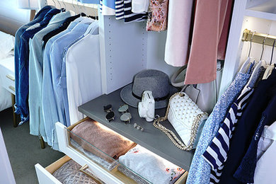 This is an example of a mid-sized transitional gender-neutral dressing room in Other with flat-panel cabinets, white cabinets, carpet and beige floor.