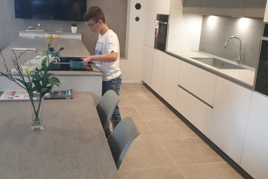 Photo of a modern galley kitchen/diner in Belfast with a submerged sink, quartz worktops, grey splashback, engineered quartz splashback, integrated appliances, an island and grey worktops.