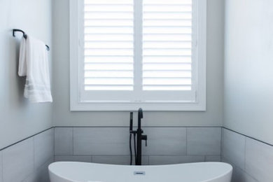 Mid-sized country master gray tile and ceramic tile laminate floor, brown floor, double-sink and shiplap wall bathroom photo in Raleigh with white cabinets, a two-piece toilet, gray walls, a drop-in sink, a hinged shower door, white countertops, a niche and a freestanding vanity