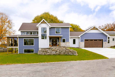 Aménagement d'une façade de maison bleue classique en panneau de béton fibré à un étage avec un toit en shingle et un toit marron.