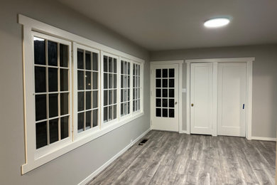 Mid-sized elegant enclosed vinyl floor and gray floor living room photo in Other with gray walls, a wood stove and a brick fireplace