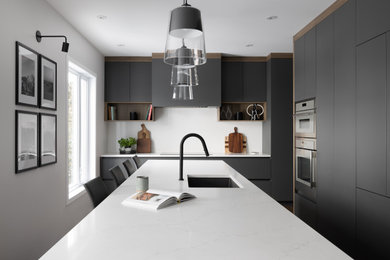 Eat-in kitchen - large contemporary dark wood floor eat-in kitchen idea in Montreal with an undermount sink, flat-panel cabinets, gray cabinets, quartz countertops, white backsplash, quartz backsplash, paneled appliances, an island and white countertops