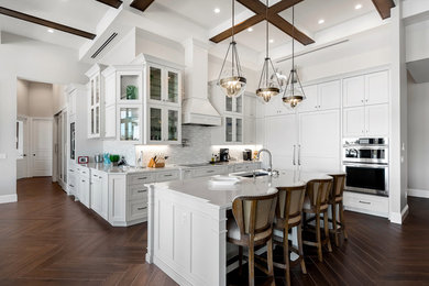 Large transitional l-shaped kitchen in Other with shaker cabinets, white cabinets, quartzite benchtops, with island, an undermount sink, white splashback, stainless steel appliances, brown floor and white benchtop.