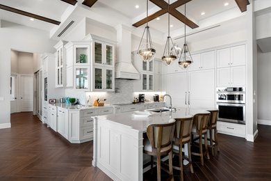 Large transitional l-shaped brown floor kitchen photo in Other with shaker cabinets, white cabinets, quartzite countertops, an island, an undermount sink, white backsplash, stainless steel appliances and white countertops