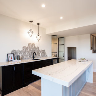 Ispirazione per un angolo bar con lavandino country di medie dimensioni con lavello sottopiano, ante con riquadro incassato, ante nere, top in marmo, paraspruzzi grigio, paraspruzzi con piastrelle in ceramica, pavimento in compensato, pavimento marrone e top bianco