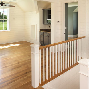 Home theater - beach style open concept light wood floor home theater idea in Charleston with beige walls and a wall-mounted tv