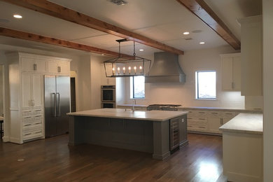 Large transitional u-shaped medium tone wood floor and brown floor open concept kitchen photo in Houston with a farmhouse sink, shaker cabinets, white cabinets, wood countertops, white backsplash, subway tile backsplash, stainless steel appliances and an island