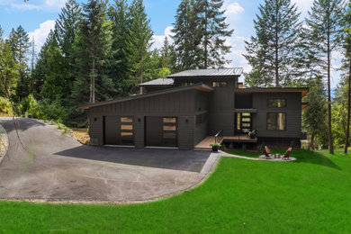 Inspiration for a mid-sized contemporary brown two-story wood and board and batten house exterior remodel in Boise with a shed roof, a metal roof and a black roof