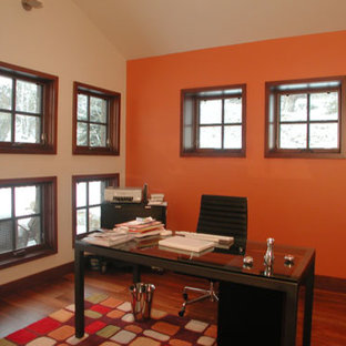 Inspiration for a medium sized modern home office and library in Denver with orange walls, medium hardwood flooring, no fireplace, a freestanding desk and beige floors.