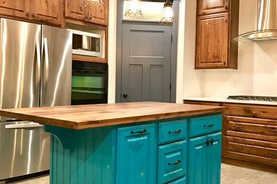 Mid-sized cottage chic l-shaped ceramic tile eat-in kitchen photo in Salt Lake City with raised-panel cabinets, medium tone wood cabinets, wood countertops, beige backsplash, stainless steel appliances and an island