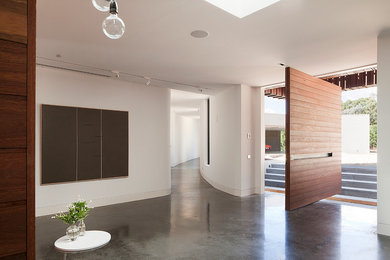 Photo of a contemporary entryway in Melbourne with concrete floors, a pivot front door and a medium wood front door.