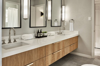 Foto de cuarto de baño principal, doble y flotante actual con armarios con paneles lisos, puertas de armario de madera clara, encimera de acrílico, suelo gris y encimeras blancas