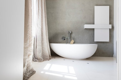 Mittelgroßes Modernes Badezimmer En Suite mit flächenbündigen Schrankfronten, grauen Schränken, freistehender Badewanne, Duschnische, Wandtoilette mit Spülkasten, Kalkfliesen, weißer Wandfarbe, Kalkstein, Wandwaschbecken, beigem Boden, Schiebetür-Duschabtrennung, grauer Waschtischplatte und beigen Fliesen in Sonstige