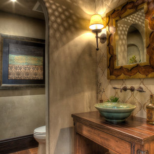 Cette photo montre une salle d'eau éclectique avec une vasque, un placard en trompe-l'oeil, des portes de placard en bois vieilli, un plan de toilette en bois, un carrelage beige, des carreaux en terre cuite, un mur beige et un sol en carreau de terre cuite.