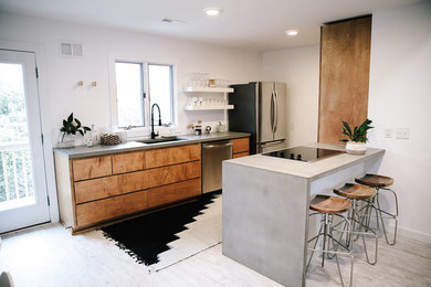Example of a minimalist laminate floor eat-in kitchen design in Other with an undermount sink, flat-panel cabinets, medium tone wood cabinets, concrete countertops, stainless steel appliances and a peninsula