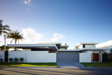 This is an example of a large midcentury two-storey white exterior in Gold Coast - Tweed with a flat roof.