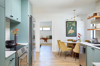 Inspiration for a small 1950s galley light wood floor and brown floor eat-in kitchen remodel in San Francisco with an undermount sink, flat-panel cabinets, green cabinets, quartz countertops, white backsplash, ceramic backsplash, stainless steel appliances, no island and white countertops