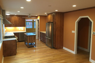 Inspiration for a small timeless l-shaped medium tone wood floor eat-in kitchen remodel in Orange County with flat-panel cabinets, dark wood cabinets, stainless steel appliances and an island