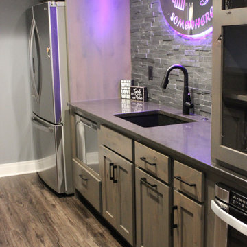 Lower Level Bar With Whiskey Barrel Planks, Gray Cabinets, and Black Quartz