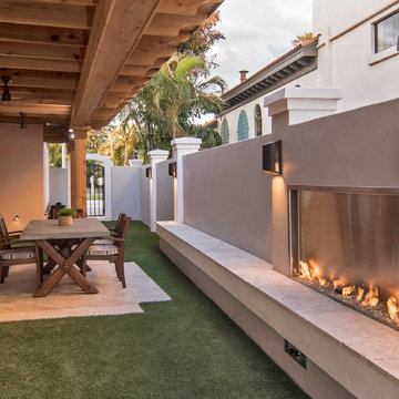Walled-in outdoor covered lanai with custom fireplace and artificial greens
