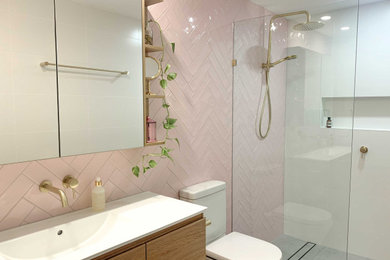 На фото: главная ванная комната среднего размера в современном стиле с плоскими фасадами, светлыми деревянными фасадами, душем без бортиков, унитазом-моноблоком, розовой плиткой, керамической плиткой, белыми стенами, полом из керамогранита, монолитной раковиной, столешницей из искусственного камня, серым полом, открытым душем, белой столешницей, нишей, тумбой под одну раковину и подвесной тумбой