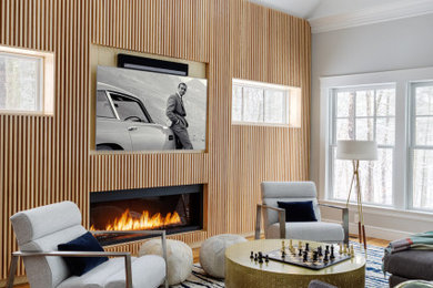 Inspiration for a contemporary living room in Boston with grey walls, medium hardwood floors, a ribbon fireplace, a wood fireplace surround, a wall-mounted tv, brown floor and wood walls.