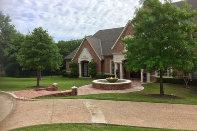 Photo of a mid-sized traditional full sun front yard brick water fountain landscape in Dallas.