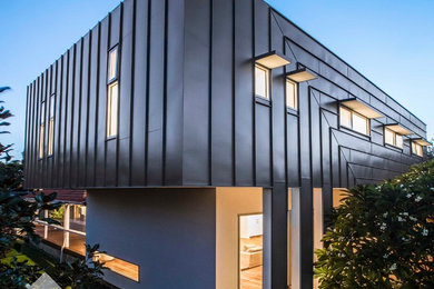 Imagen de fachada de casa gris y gris moderna de tamaño medio de dos plantas con revestimiento de metal, tejado de un solo tendido y tejado de metal