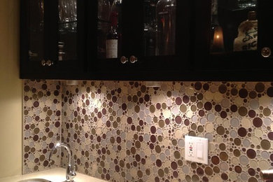 Example of a small classic single-wall beige floor wet bar design in Los Angeles with shaker cabinets, dark wood cabinets, solid surface countertops, multicolored backsplash, an undermount sink and mosaic tile backsplash