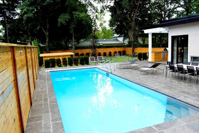 Inspiration for a large modern backyard rectangular lap pool in Toronto with natural stone pavers.