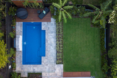 Design ideas for a mid-sized tropical backyard full sun garden in Brisbane with natural stone pavers.