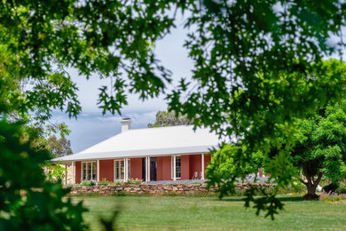 Design ideas for a large country one-storey stucco red exterior in Sydney with a hip roof.