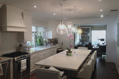 Photo of a mid-sized transitional single-wall separate kitchen in Miami with raised-panel cabinets, white cabinets, quartz benchtops, white splashback, ceramic splashback, stainless steel appliances, dark hardwood floors and with island.