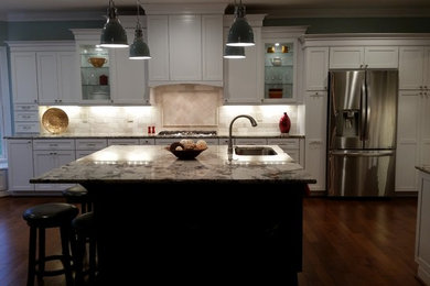 Huge transitional l-shaped medium tone wood floor open concept kitchen photo in Richmond with an undermount sink, recessed-panel cabinets, white cabinets, glass countertops, beige backsplash, subway tile backsplash, stainless steel appliances and an island