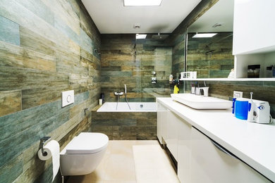 Example of a trendy 3/4 limestone floor tub/shower combo design in Denver with flat-panel cabinets, white cabinets, a one-piece toilet, a vessel sink and solid surface countertops