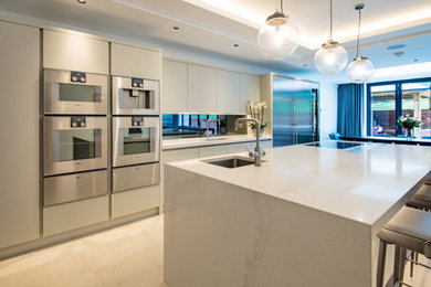Inspiration for a large contemporary kitchen/diner in Hertfordshire with flat-panel cabinets, mirror splashback, stainless steel appliances, porcelain flooring, an island and white worktops.